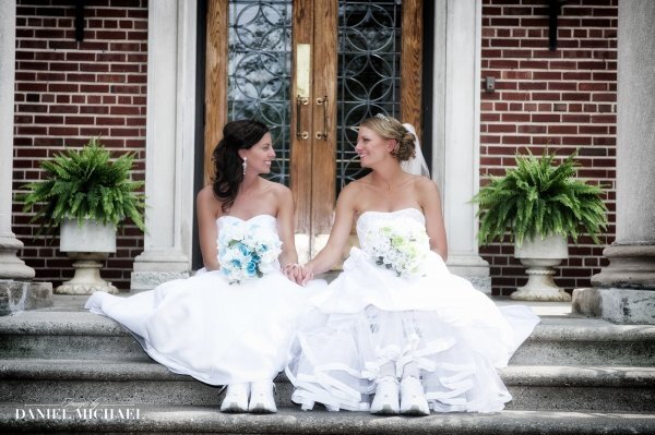 two brides sitting on steps as they smile at each other